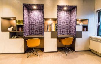 Furnished office space available for rent at Prins Bernhardplein 200, Amsterdam Amstel, featuring two modern workspaces with built-in shelves and comfortable chairs.