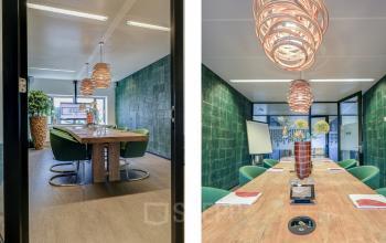 Inviting office space with a large wooden table, green chairs, and modern lighting at Prins Bernhardplein 200, Amsterdam Amstel, perfect for office space rental.