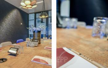 Modern conference room at Prins Bernhardplein 200, Amsterdam Amstel, featuring a wooden table, blue accent chairs, and pendant lighting, ideal for office space rental.