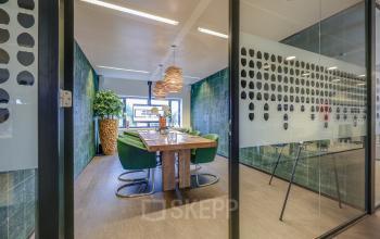 Modern furnished conference room at Prins Bernhardplein 200, Amsterdam Amstel, featuring a wooden table and green chairs, ideal for office space rental.