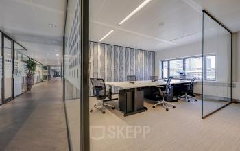 Modern office space with glass partitions at Prins Bernhardplein 200, Amsterdam Amstel, ideal for office space rental. Bright workspace with chairs and desks offering plenty of natural light.