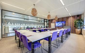 Spacious conference room with purple chairs and large screen at Prins Bernhardplein 200, ideal for office space rental in Amsterdam Amstel.