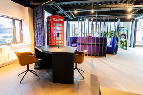 Modern office space rental at Prins Bernhardplein 200, Amsterdam Amstel, featuring a bright open-floor design with desks, a phone booth, and seating area.