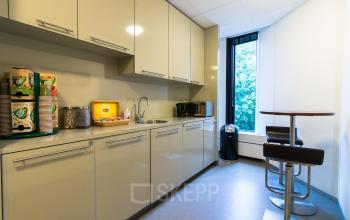 Modern and well-equipped pantry area available for office space rental at De Cuserstraat 93, in Amsterdam Buitenveldert, with white cabinets and appliances.