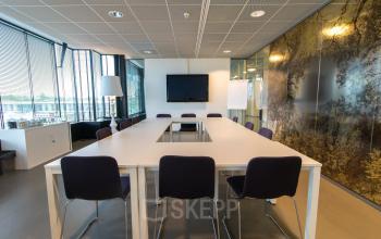 Modern conference room with a large table, chairs, and presentation screen in De Cuserstraat 93, ideal for office space rental in Amsterdam Buitenveldert.