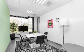 Clean and well-lit office space rental at De Cuserstraat 93, Amsterdam Buitenveldert with modern furniture and a vibrant wall art.