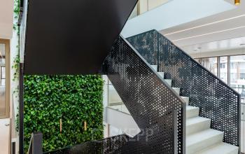 Modern office space with a striking staircase and lush greenery wall, perfect for office space rental at Walborg 2A in Amsterdam Buitenveldert.