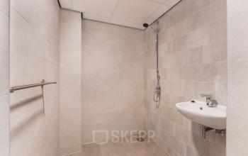 An unfurnished restroom with a sink and shower, ideal for office space rental at Walborg 2A, Amsterdam Buitenveldert.