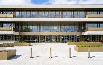Exterior view of an office building located at Walborg 2A, Amsterdam Buitenveldert, showcasing a modern facade with large glass windows and a concrete entrance area suitable for office space rental.
