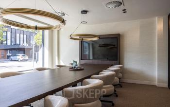 Modern conference room with a long wooden table and comfortable chairs near a large window in Zwaansvliet 1, Amsterdam Buitenveldert, ideal for office space rental.