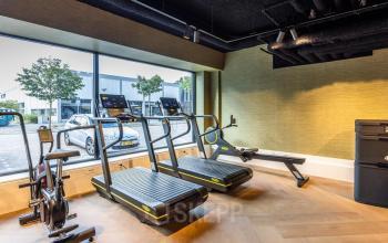 Office space rental gym area with treadmills and exercise bikes by a large window at Zwaansvliet 1, Amsterdam Buitenveldert.