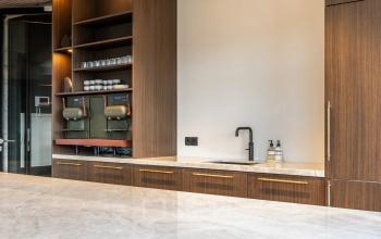 Modern office pantry with wooden cabinetry, marble countertops, coffee machines, and a sink at Zwaansvliet 1, Amsterdam Buitenveldert; perfect for office space rental seekers.