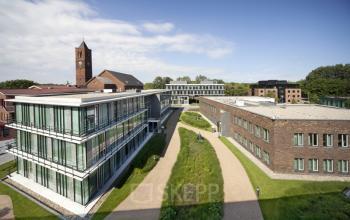 Exterior view of modern office buildings at De Cuserstraat 91, Amsterdam Buitenveldert, featuring glass facades and landscaped paths, suitable for office space rental.