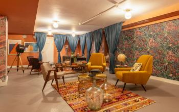 Cozy and vibrant lounge area featuring a variety of comfortable seating options, colorful rugs, and eclectic decor at Nieuwezijds Voorburgwal 296-298 in Amsterdam Center, available for office space rental.