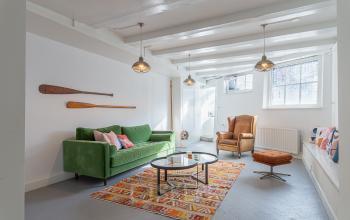 Modern office interior at Nieuwezijds Voorburgwal 296-298, Amsterdam Center, featuring a cozy seating area with a green sofa, leather armchair, and a decorative rug, ideal for office space rental.
