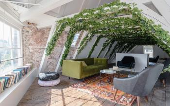 Cozy office space rental with greenery on the attic level, featuring stylish furniture and large windows at Nieuwezijds Voorburgwal 296-298, Amsterdam Center.