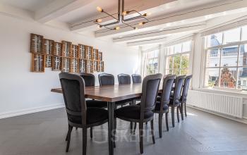 Bright conference room with a large wooden table and black chairs at Nieuwezijds Voorburgwal 296-298, Amsterdam Center, available for office space rental.
