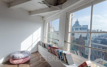 Bright workspace with large windows and a bookshelf overlooking Nieuwezijds Voorburgwal 296-298 in Amsterdam Center.