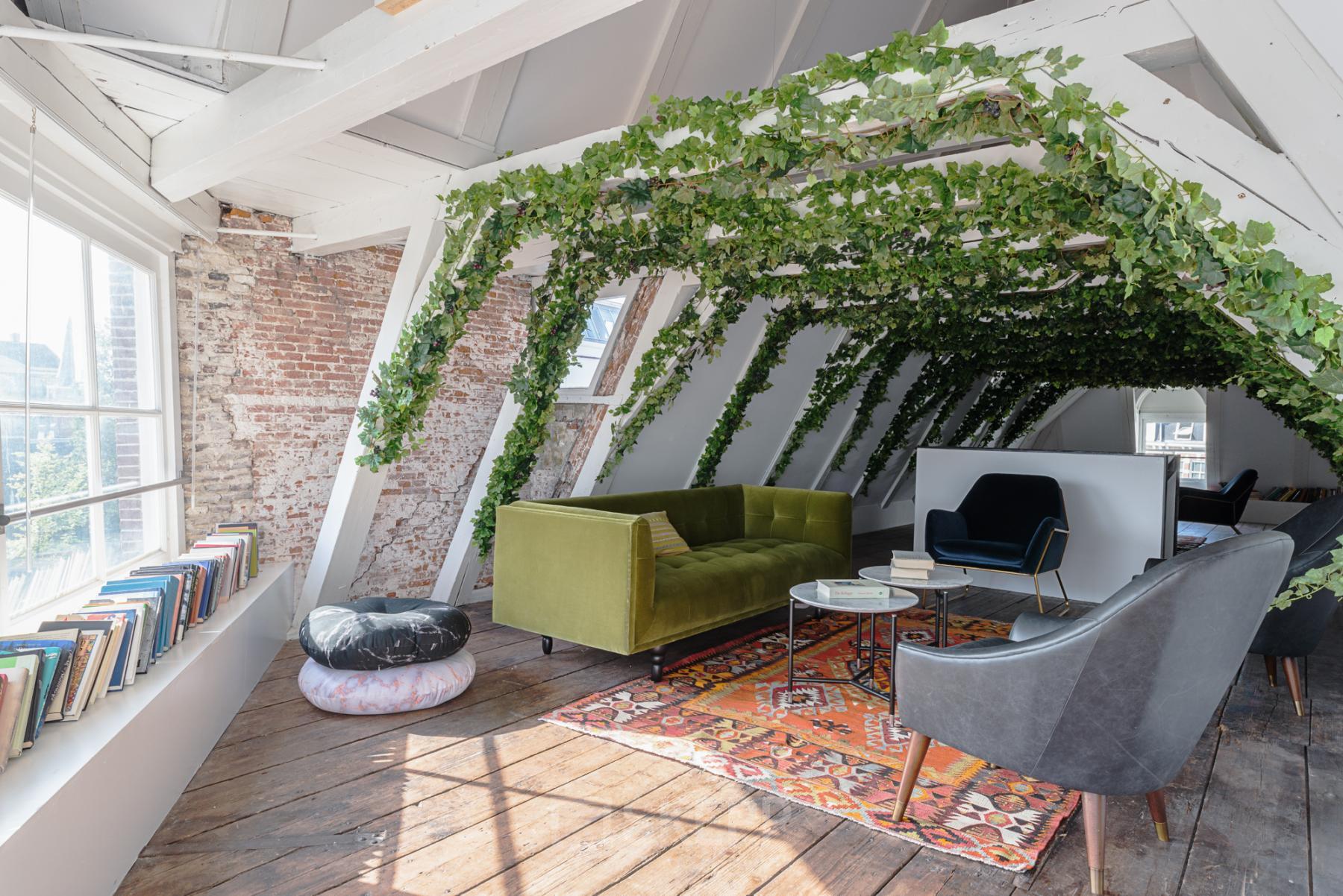 Cozy office space rental with greenery on the attic level, featuring stylish furniture and large windows at Nieuwezijds Voorburgwal 296-298, Amsterdam Center.