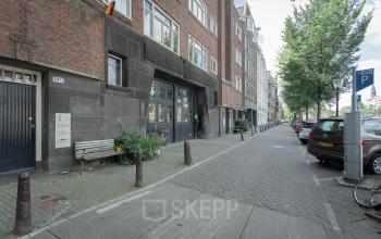 Exterior view of a neat office space rental located at Oudeschans 21, in Amsterdam Center, Amsterdam, with large windows and a bench outside.
