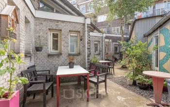 Inviting courtyard office space rental at Oudeschans 21, Amsterdam Center, with outdoor seating and lush potted plants.