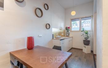 Cozy office space rental at Oudeschans 21, Amsterdam Center, with a wooden table, decorative mirrors, and ample natural light.