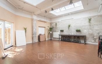 Spacious office space rental at Oudeschans 21 with natural light, modern fixtures, and green plant accents in Amsterdam Center.