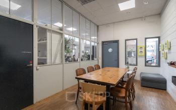 Modern office space rental at Oudeschans 21, Amsterdam Center, with a large wooden table and natural light.