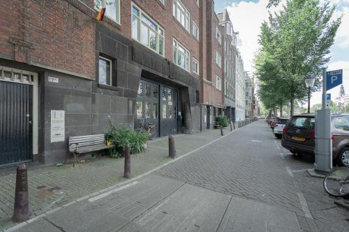 Exterior view of a neat office space rental located at Oudeschans 21, in Amsterdam Center, Amsterdam, with large windows and a bench outside.