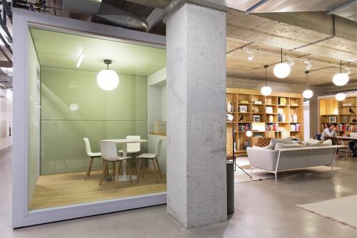 Modern office space at Vijzelstraat 68-78, Amsterdam Center, featuring a cozy meeting area with glass walls, minimalist design, and wooden shelves.