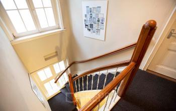 Staircase with wooden railing and carpeted steps in an office building located at Schippersgracht 1-3, Amsterdam Center, Amsterdam.