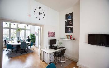 Office space at Schippersgracht 1-3, Amsterdam Center, Amsterdam with desks, chairs, computer station, and wall clock in a bright room with large windows.
