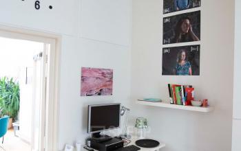Modern office space rental at Schippersgracht 1-3, Amsterdam Center, with a desk, computer, wall clock, and shelves in a bright room.