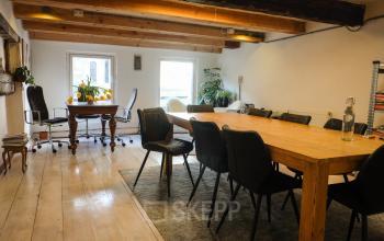 Spacious office with wooden beams and a long table, perfect for meetings, located in Amsterdam Center. Ideal office space rental with natural light.