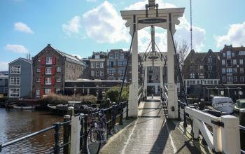 Scenic view of a bridge near office space rental at Prinseneiland 23A, Amsterdam Center with surrounding traditional buildings and a bicycle parked nearby.