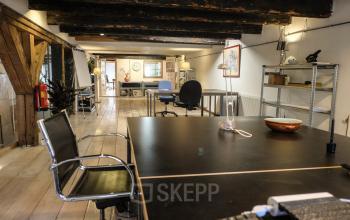 Rustic office space with wooden beams, modern desks, and chairs available for rent on Prinseneiland 23A, Amsterdam Center.