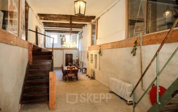 Interior view of a rustic office space at Prinseneiland 23A, with a wooden table and chairs under warm lighting, available for rent in Amsterdam Center.