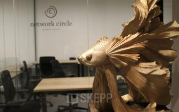 Interior office space at Network Circle, Hekelveld 8-10, Amsterdam Center, featuring a striking golden fish sculpture with modern workstations in the background.