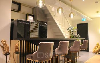 Modern lounge area with sleek bar, plush seating, and decorative accents at Hekelveld 8-10, Amsterdam Center. Ideal for office space rental.