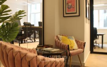 Chic office lounge at Hekelveld 8-10, featuring stylish pink chairs, framed art, and a cozy ambiance perfect for informal meetings or breaks. Ideal for office space rental in Amsterdam Center.