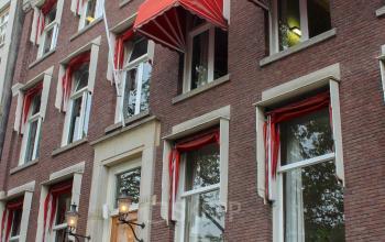 Exterior view of an office building at Singel 126 in Amsterdam Center, showcasing multiple windows with red awnings. Ideal for office space rental.
