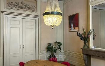 Elegant office space on Singel 126, Amsterdam Center, featuring a wooden table, vintage chandelier, and seating. Ideal for office space rental.