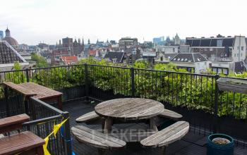 Rooftop terrace at Singel 126, Amsterdam Center, featuring a wooden table and benches with city views, ideal for a casual meeting or break. Available for office space rental.