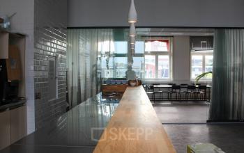 Bright office space at Singel 126, Amsterdam Center, featuring a sleek conference room with a long wooden table and modern lighting, ideal for office space rental.