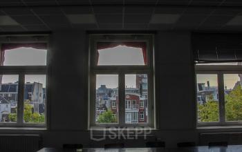 Interior view from the office space rental at Singel 126, Amsterdam Center, featuring large windows with city views.