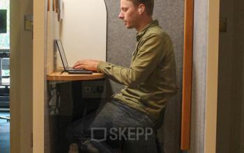 Individual working in a modern office space rental booth at Singel 126, Amsterdam Center, ideal for focused tasks.