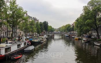 View of canal in Amsterdam Center near Singel 126, showcasing boats and lush greenery, ideal for an office to rent nearby.