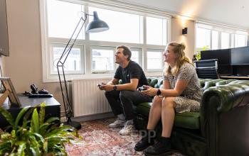 Two people sitting on a couch in an office at Singel 126, Amsterdam Center, appear to be working together casually with laptops on a furnished indoor setting. Perfect office space rental option.
