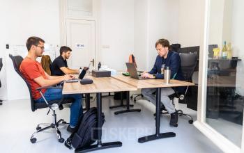 Three people working diligently at their laptops in a furnished office space at Singel 126, Amsterdam Center, ideal for office space rental.
