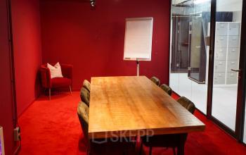A furnished conference room with a large wooden table and seven chairs, located at Weesperplein 4b, Amsterdam Center. Ideal for office space rental or finding an office to rent.